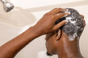 black man washing hair in shower